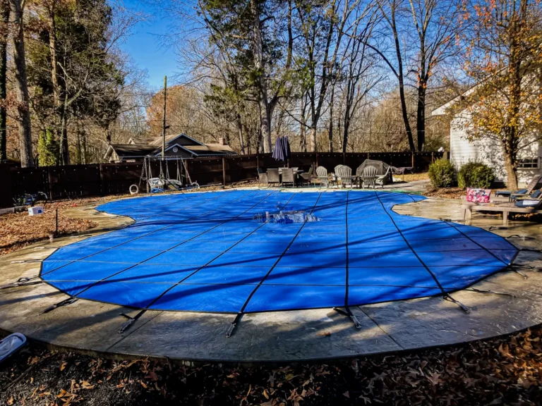 blue solid safety covered pool with a wooded background